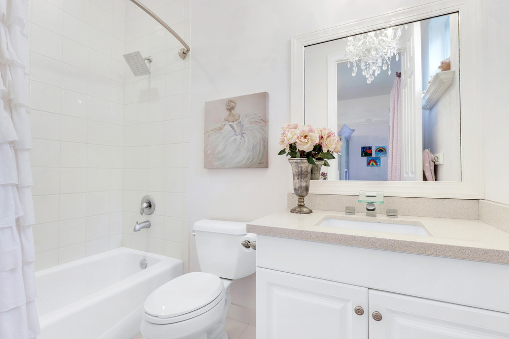 Large modern kids bathroom in Miami with white cabinets, an alcove tub, an alcove shower, a one-piece toilet, mirror tile, white walls, an undermount sink, concrete benchtops, beige floor and a shower curtain.
