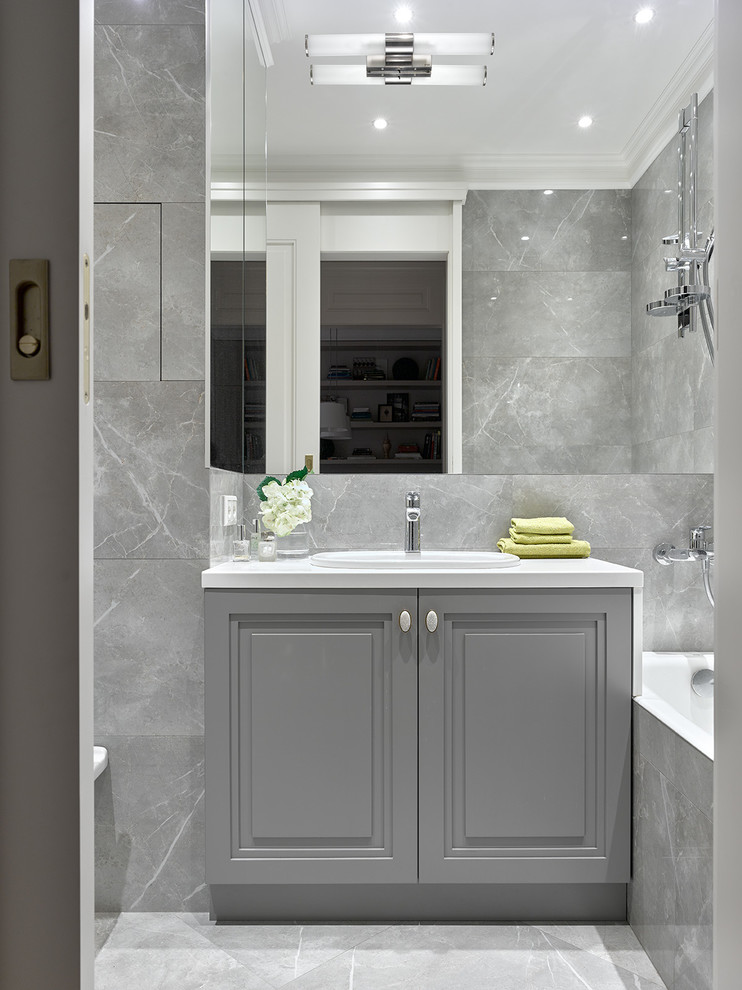 This is an example of a mid-sized transitional master bathroom in Other with gray tile, ceramic tile, tile benchtops, raised-panel cabinets, grey cabinets, an alcove tub, a shower/bathtub combo, a drop-in sink, grey floor, grey walls, marble floors and an open shower.