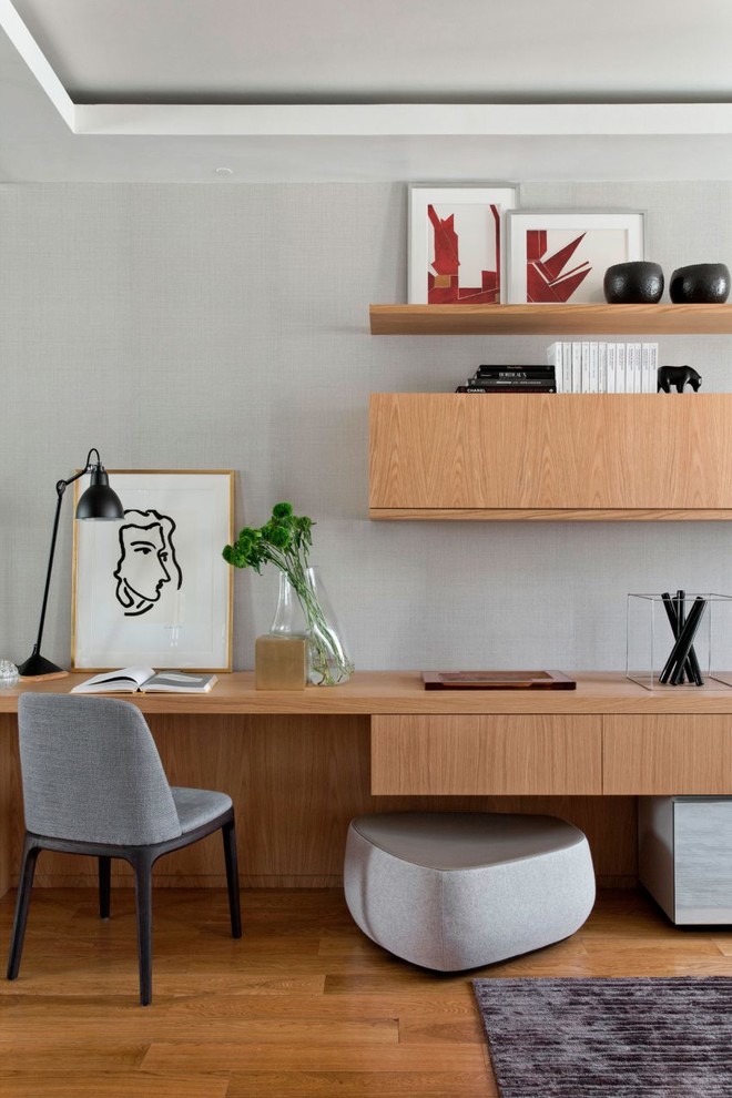 Design ideas for a mid-sized contemporary home office in Mumbai with grey walls, medium hardwood floors and a built-in desk.