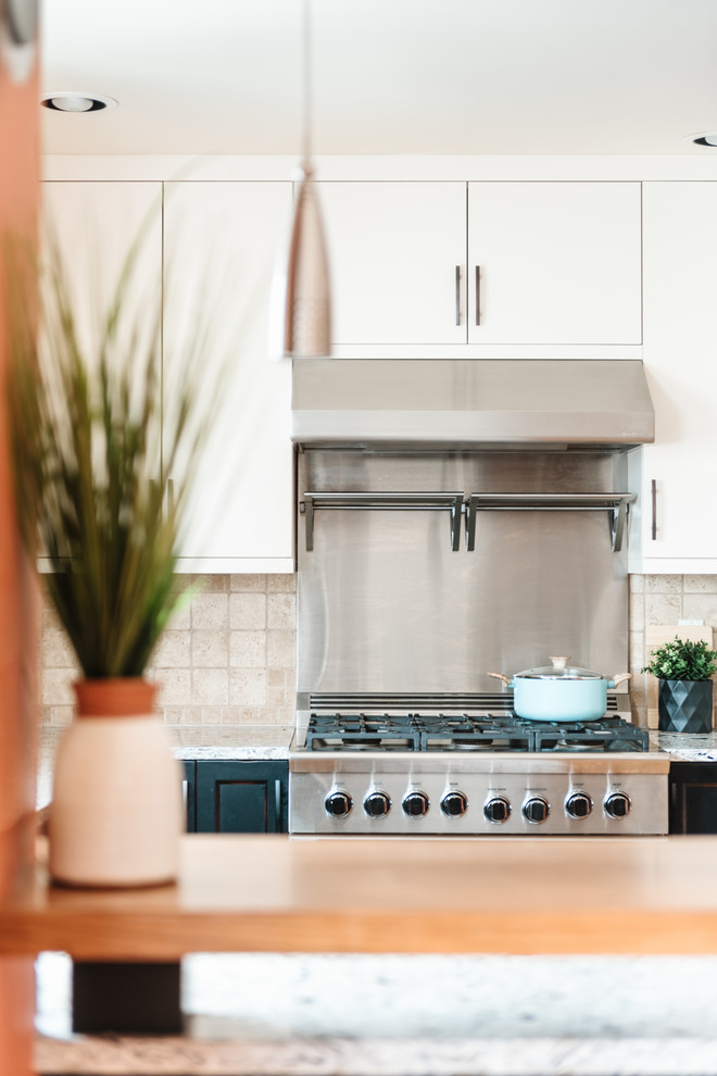 Example of a mid-sized transitional u-shaped medium tone wood floor and brown floor eat-in kitchen design with an undermount sink, shaker cabinets, distressed cabinets, quartz countertops, white backsplash, travertine backsplash, stainless steel appliances, a peninsula and multicolored countertops