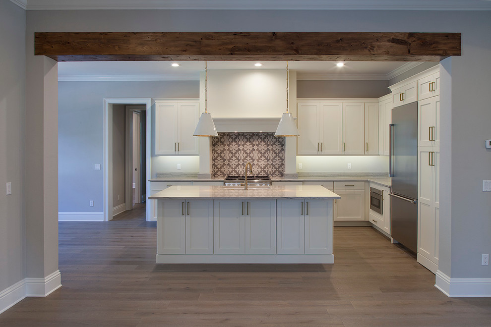 Example of a large transitional u-shaped light wood floor eat-in kitchen design in Orlando with a farmhouse sink, shaker cabinets, white cabinets, granite countertops, white backsplash, stainless steel appliances and an island