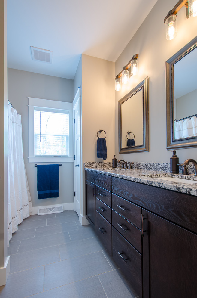 Mid-sized transitional tub/shower combo photo with shaker cabinets, dark wood cabinets, gray walls, an undermount sink and granite countertops