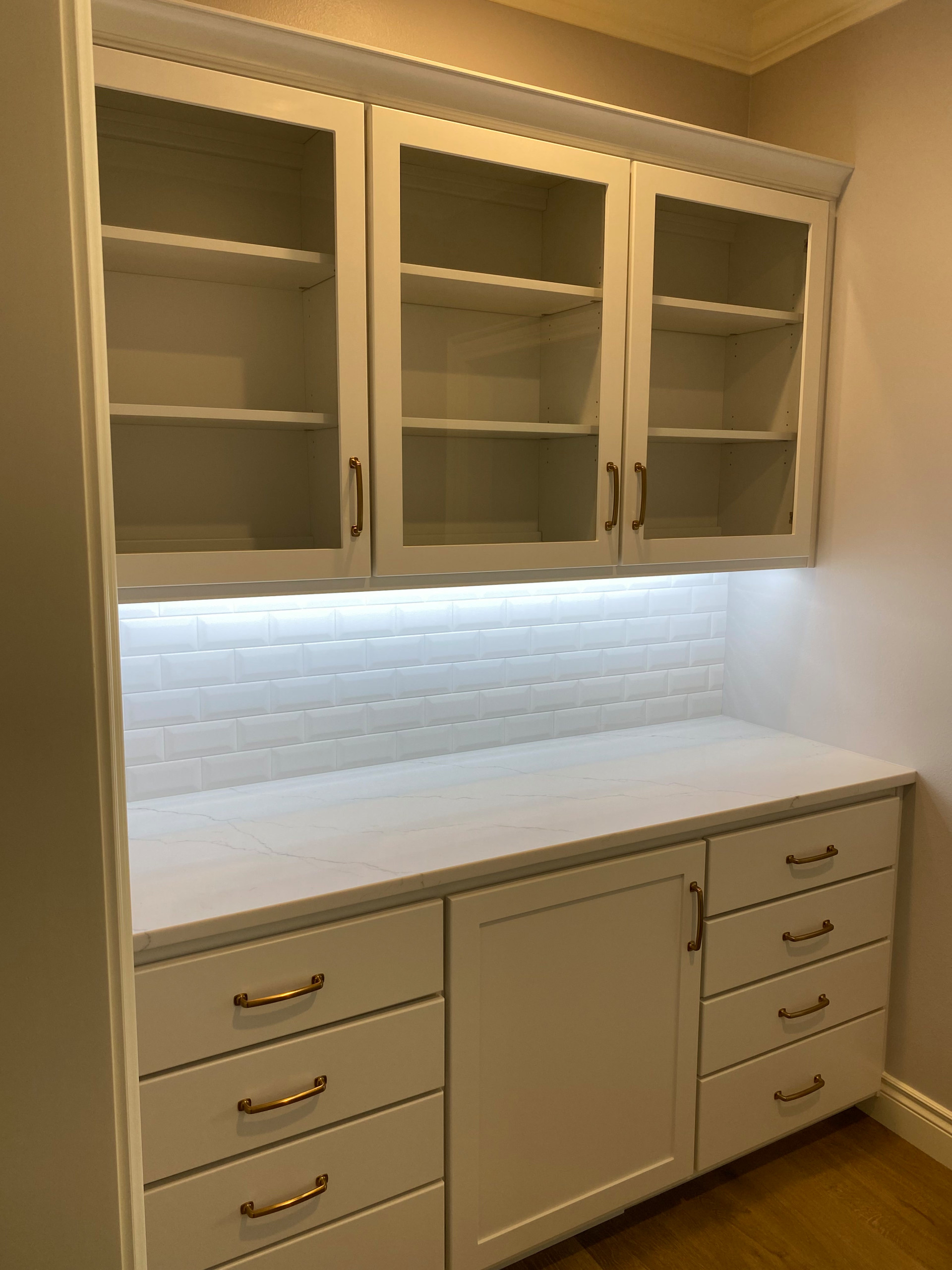 Butlers pantry with white painted custom cabinetry, quartz countertop, and subwa