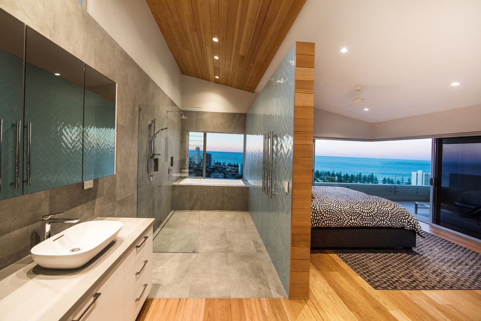 Large contemporary master bathroom in Gold Coast - Tweed with white cabinets, a drop-in tub, an open shower, a one-piece toilet, blue tile, ceramic tile, grey walls, ceramic floors, a vessel sink, engineered quartz benchtops, grey floor, an open shower and grey benchtops.