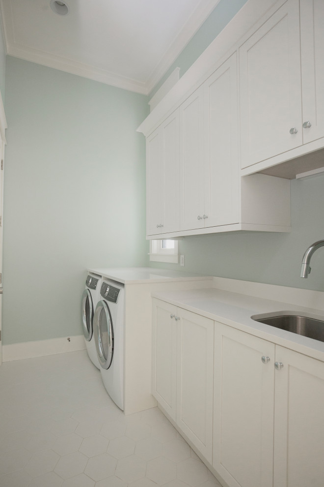 This is an example of a mid-sized beach style single-wall dedicated laundry room in Orlando with a single-bowl sink, shaker cabinets, white cabinets, quartzite benchtops, white splashback, engineered quartz splashback, green walls, ceramic floors, a side-by-side washer and dryer, white floor, white benchtop and recessed.