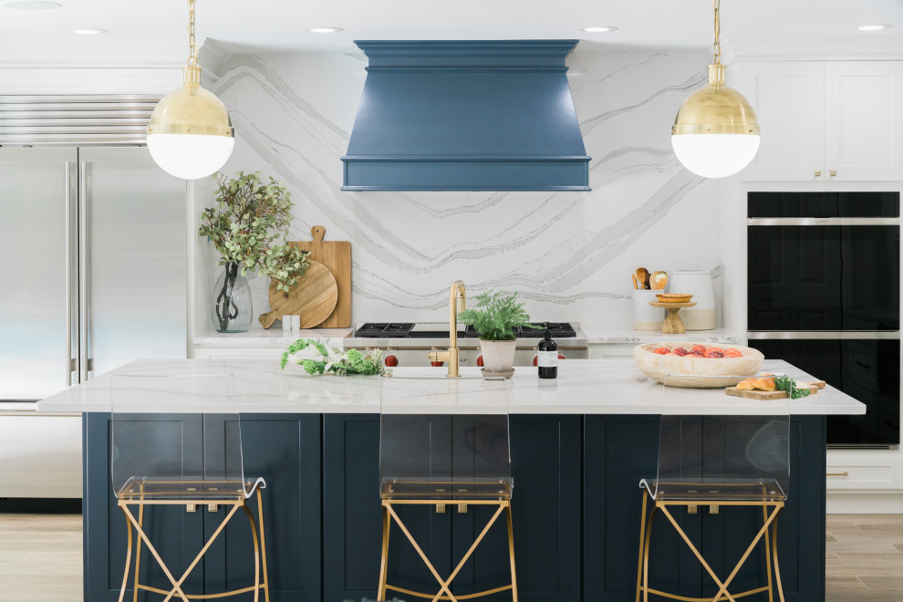 Example of a transitional galley beige floor kitchen design in Tampa with a farmhouse sink, shaker cabinets, white cabinets, white backsplash, stone slab backsplash, an island and white countertops