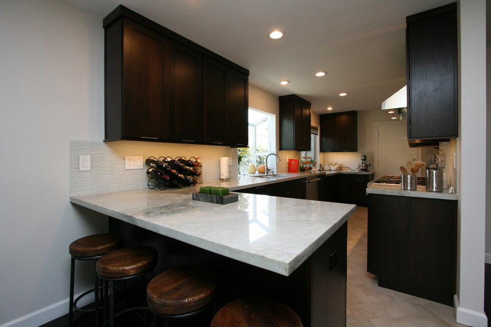 Mid-sized transitional l-shaped porcelain tile kitchen photo in Orange County with a double-bowl sink, recessed-panel cabinets, dark wood cabinets, quartzite countertops, white backsplash, glass tile backsplash, stainless steel appliances and no island