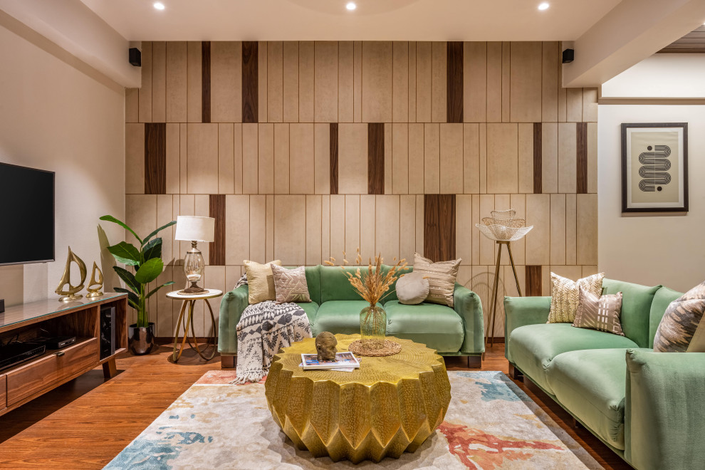 This is an example of a modern living room in Mumbai with beige walls, light hardwood floors, a wall-mounted tv, brown floor and panelled walls.