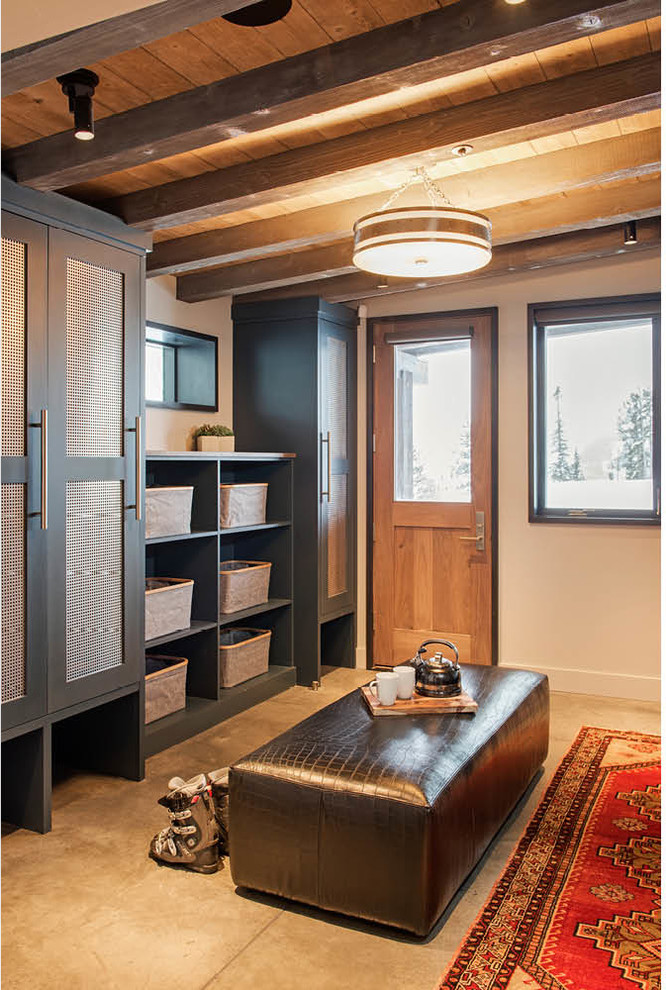 This is an example of a mid-sized country mudroom in Other with white walls, concrete floors, a single front door, a medium wood front door and grey floor.