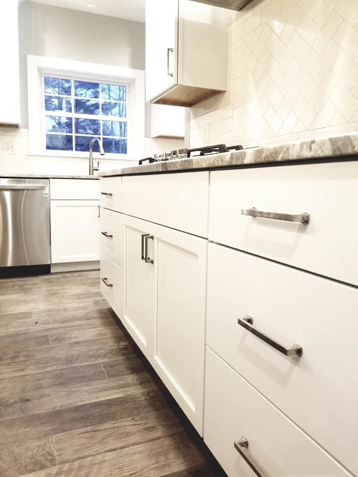 Inspiration for a transitional brown floor kitchen remodel with an undermount sink, flat-panel cabinets, white cabinets, quartzite countertops, white backsplash, subway tile backsplash, stainless steel appliances and an island