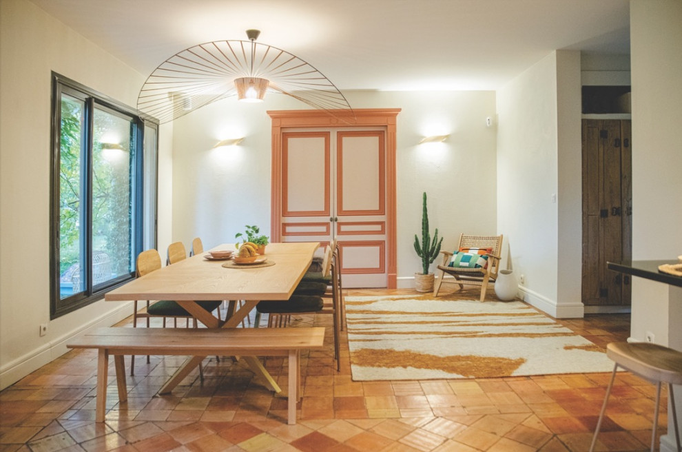Esempio di una grande sala da pranzo aperta verso il soggiorno minimalista con pareti beige, pavimento in terracotta, nessun camino e pavimento arancione