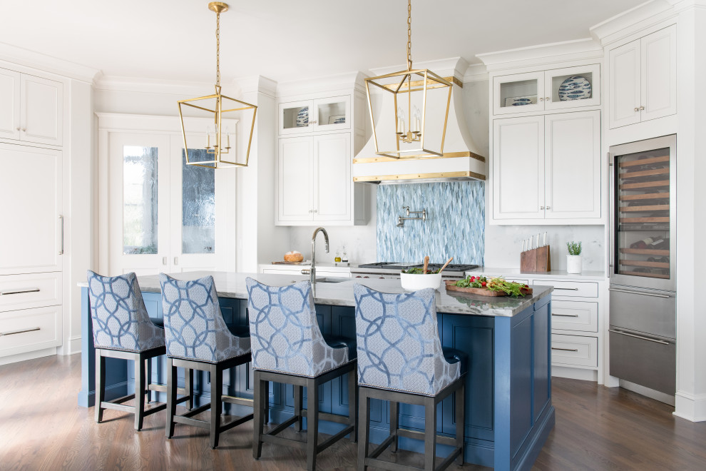 This is an example of a beach style u-shaped kitchen in Charleston with a farmhouse sink, white cabinets, marble benchtops, blue splashback, mosaic tile splashback, stainless steel appliances, with island, recessed-panel cabinets, dark hardwood floors, brown floor and white benchtop.