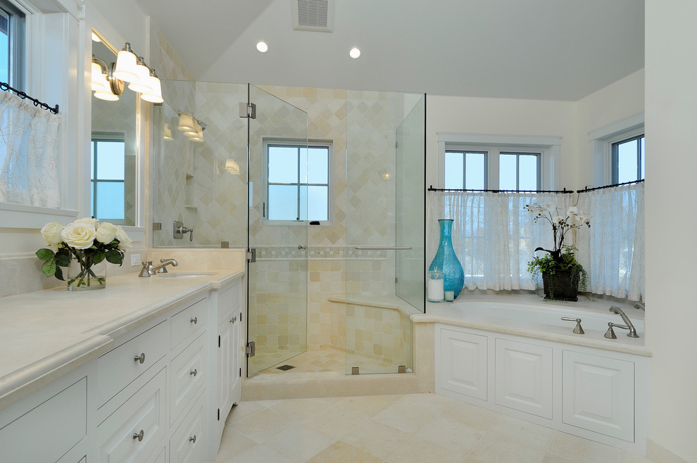 Inspiration for a mid-sized arts and crafts master bathroom in Santa Barbara with beaded inset cabinets, white cabinets, an undermount tub, a corner shower, beige tile, stone tile, white walls, travertine floors, an undermount sink, engineered quartz benchtops, a two-piece toilet, beige floor and a hinged shower door.