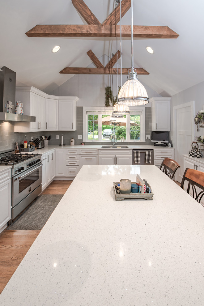 Mid-sized transitional u-shaped eat-in kitchen in Bridgeport with a single-bowl sink, raised-panel cabinets, white cabinets, granite benchtops, grey splashback, ceramic splashback, stainless steel appliances, with island, brown floor, multi-coloured benchtop and light hardwood floors.
