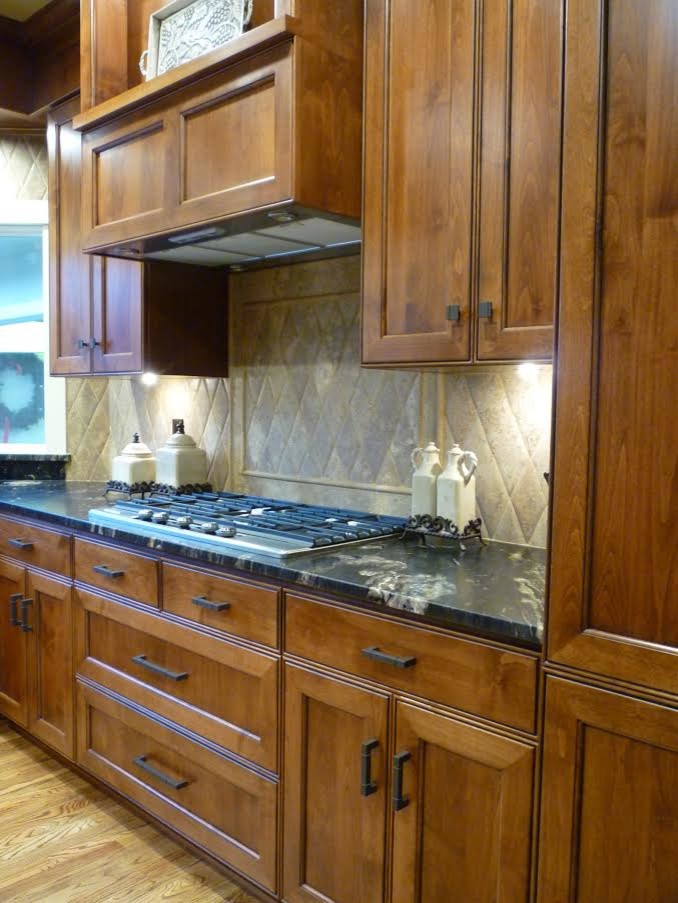 Example of a small transitional u-shaped medium tone wood floor eat-in kitchen design with recessed-panel cabinets, medium tone wood cabinets, granite countertops, stone tile backsplash and a peninsula