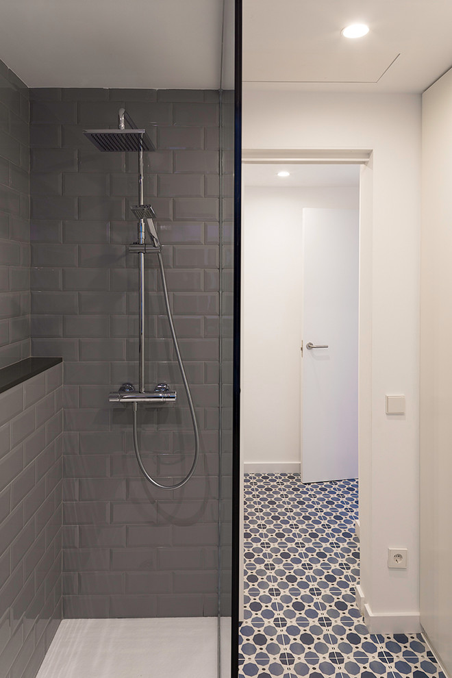 Photo of a medium sized contemporary ensuite bathroom in Barcelona with flat-panel cabinets, white cabinets, a built-in shower, grey tiles, ceramic tiles, white walls, ceramic flooring, engineered stone worktops, blue floors and black worktops.