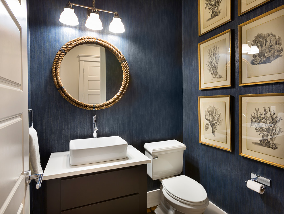 Design ideas for a beach style powder room in Charleston with flat-panel cabinets, a two-piece toilet, blue walls, a wall-mount sink and white benchtops.