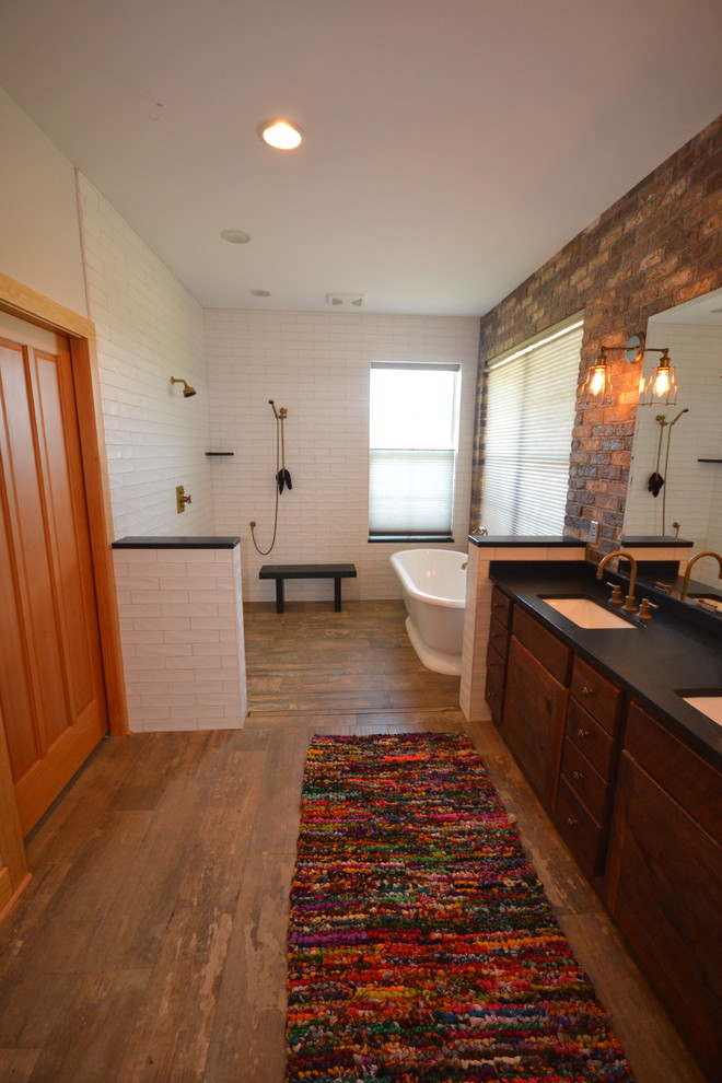 Inspiration for a mid-sized country master bathroom in Other with flat-panel cabinets, dark wood cabinets, a freestanding tub, an open shower, white tile, subway tile, dark hardwood floors, an undermount sink, solid surface benchtops, brown floor and an open shower.
