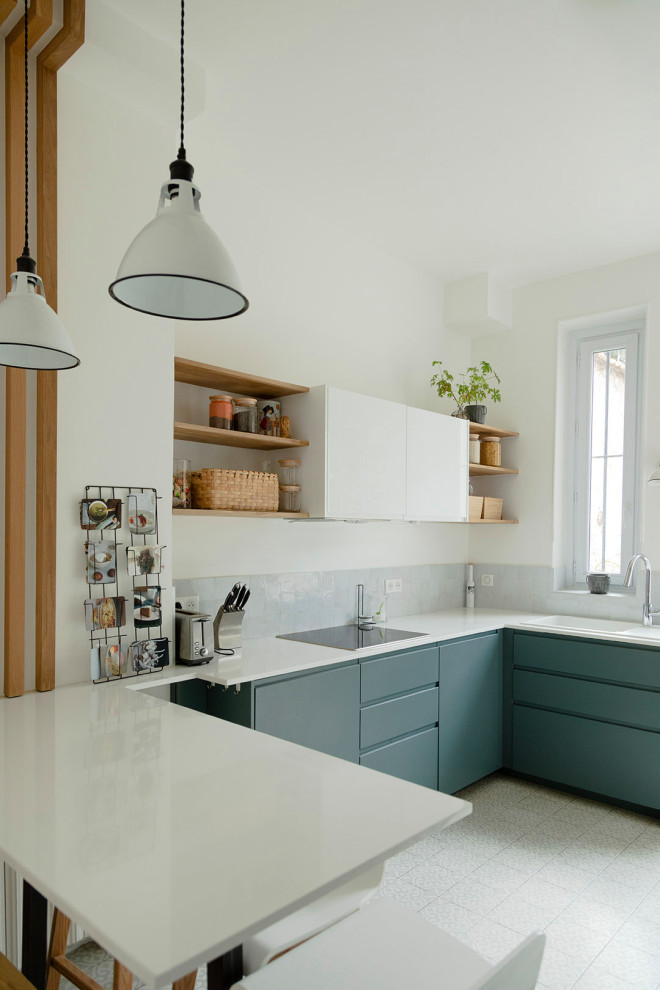 Large u-shaped eat-in kitchen in Paris with a single-bowl sink, flat-panel cabinets, green cabinets, quartzite benchtops, white splashback, terra-cotta splashback, panelled appliances, cement tiles, a peninsula, grey floor and white benchtop.