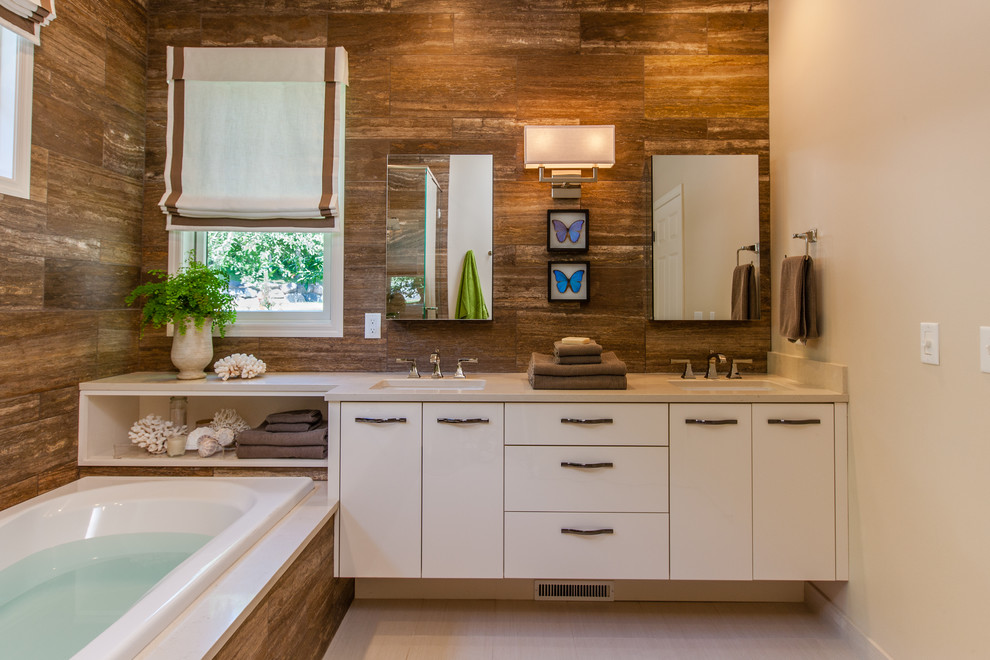 Inspiration for a large modern master bathroom in Minneapolis with flat-panel cabinets, yellow cabinets, a drop-in tub, a corner shower, brown tile, stone tile, beige walls, porcelain floors, an undermount sink and engineered quartz benchtops.