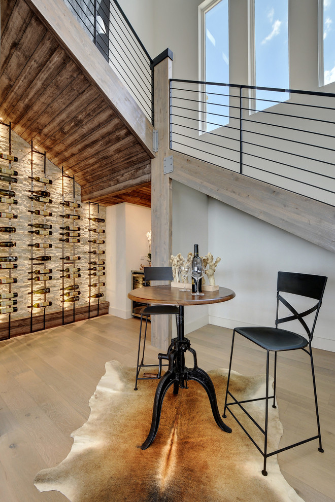 Design ideas for a mid-sized industrial wine cellar in Austin with light hardwood floors and storage racks.