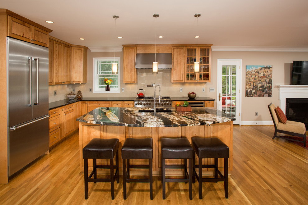 This is an example of a mid-sized traditional l-shaped open plan kitchen in DC Metro with an undermount sink, medium wood cabinets, granite benchtops, beige splashback, ceramic splashback, stainless steel appliances, medium hardwood floors and with island.