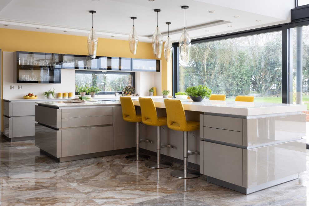 Design ideas for a large contemporary open plan kitchen in Hampshire with an integrated sink, glass-front cabinets, beige cabinets, engineered stone countertops, black appliances, porcelain flooring, an island, beige floors and beige worktops.