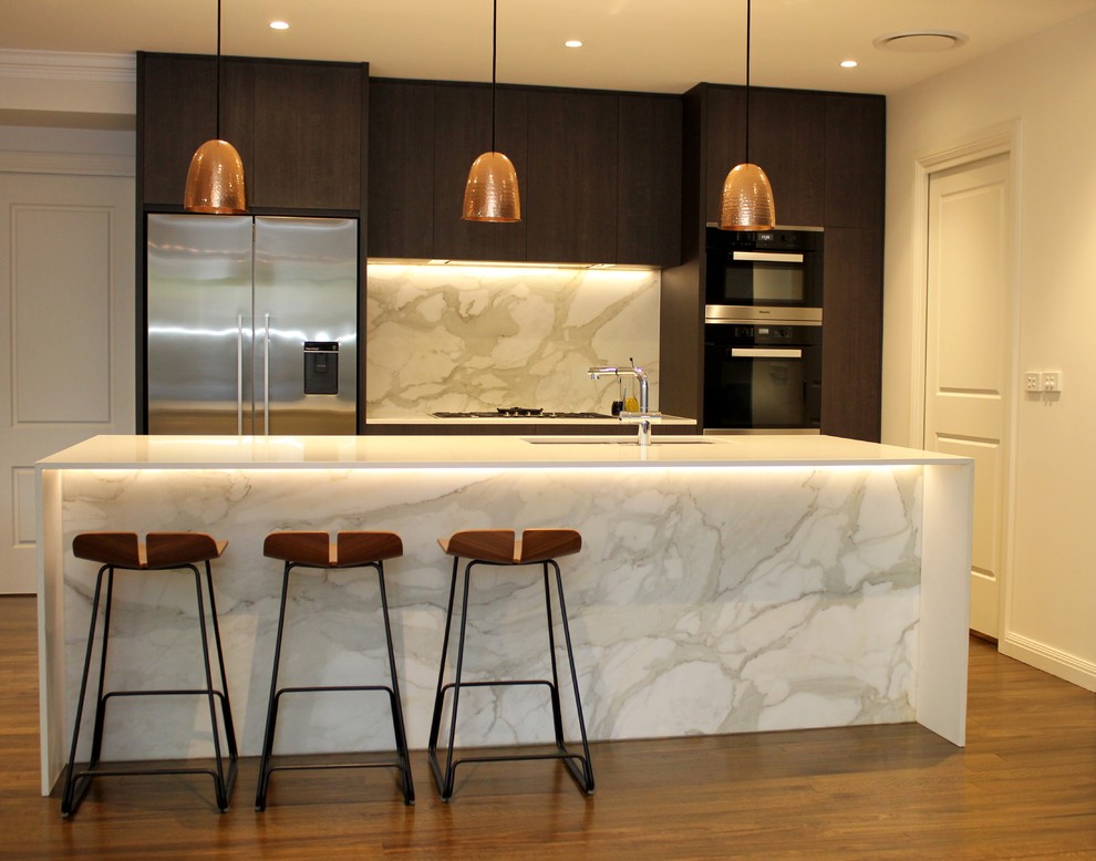 Photo of a mid-sized contemporary single-wall open plan kitchen in Sydney with an undermount sink, flat-panel cabinets, dark wood cabinets, solid surface benchtops, marble splashback, stainless steel appliances, medium hardwood floors and with island.