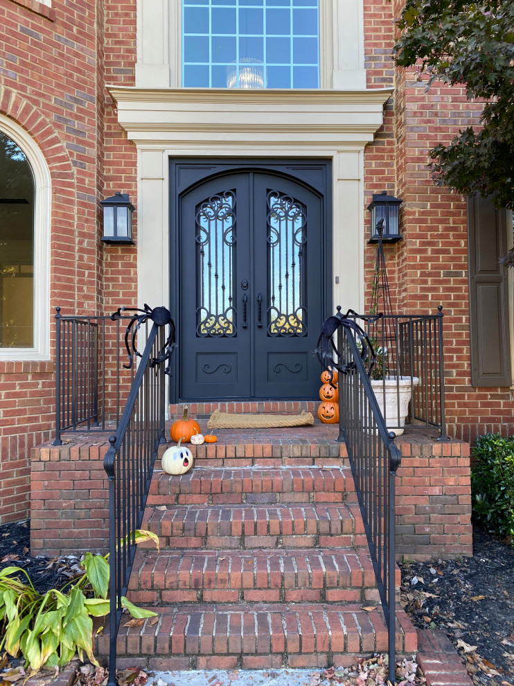 На фото: маленькая входная дверь в стиле кантри с двустворчатой входной дверью и черной входной дверью для на участке и в саду с