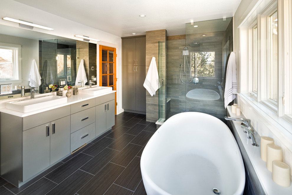 Design ideas for a large transitional master bathroom in Denver with flat-panel cabinets, grey cabinets, a freestanding tub, an alcove shower, a one-piece toilet, gray tile, porcelain tile, white walls, porcelain floors, a drop-in sink and engineered quartz benchtops.