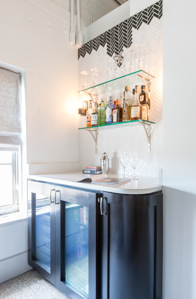 This is an example of a small eclectic single-wall home bar in Dallas with black cabinets, white splashback, ceramic splashback and white benchtop.