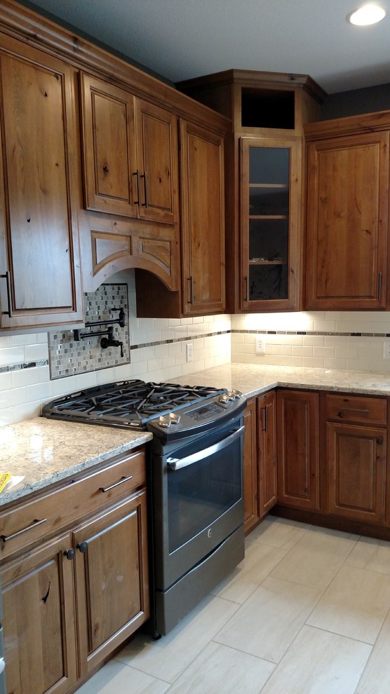 Design ideas for a mid-sized country l-shaped kitchen in Indianapolis with a farmhouse sink, raised-panel cabinets, medium wood cabinets, quartzite benchtops, white splashback, subway tile splashback, coloured appliances and vinyl floors.