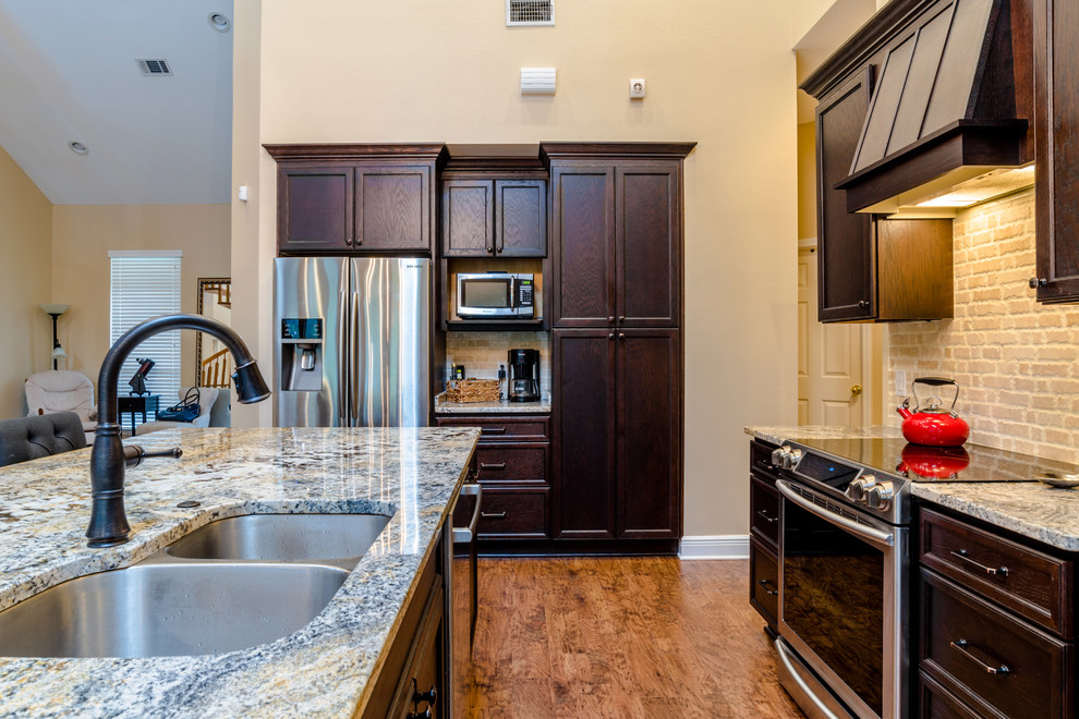 Example of a large transitional l-shaped vinyl floor eat-in kitchen design in Miami with an undermount sink, shaker cabinets, dark wood cabinets, granite countertops, beige backsplash, porcelain backsplash, stainless steel appliances and an island
