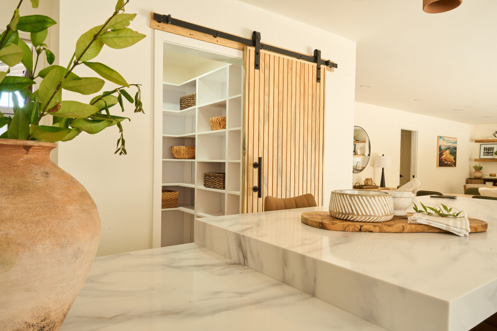 Example of a large transitional u-shaped vinyl floor and brown floor kitchen pantry design in Orange County with an undermount sink, shaker cabinets, white cabinets, quartz countertops, white backsplash, quartz backsplash, stainless steel appliances, two islands and white countertops