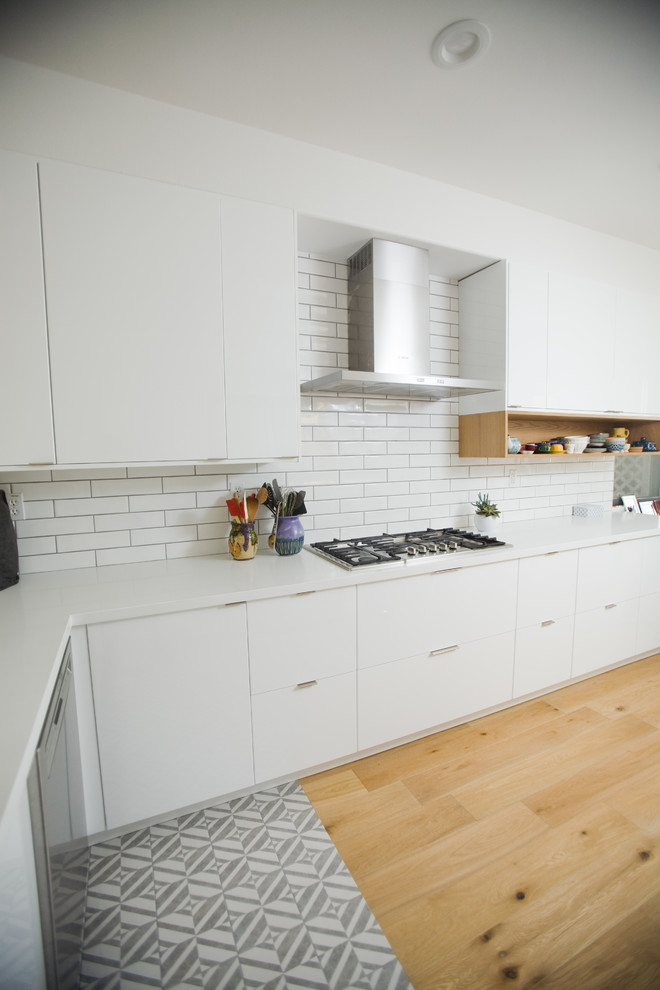 Inspiration for a mid-sized scandinavian u-shaped separate kitchen in Los Angeles with a drop-in sink, flat-panel cabinets, white cabinets, quartz benchtops, white splashback, subway tile splashback, stainless steel appliances, cement tiles, no island and multi-coloured floor.