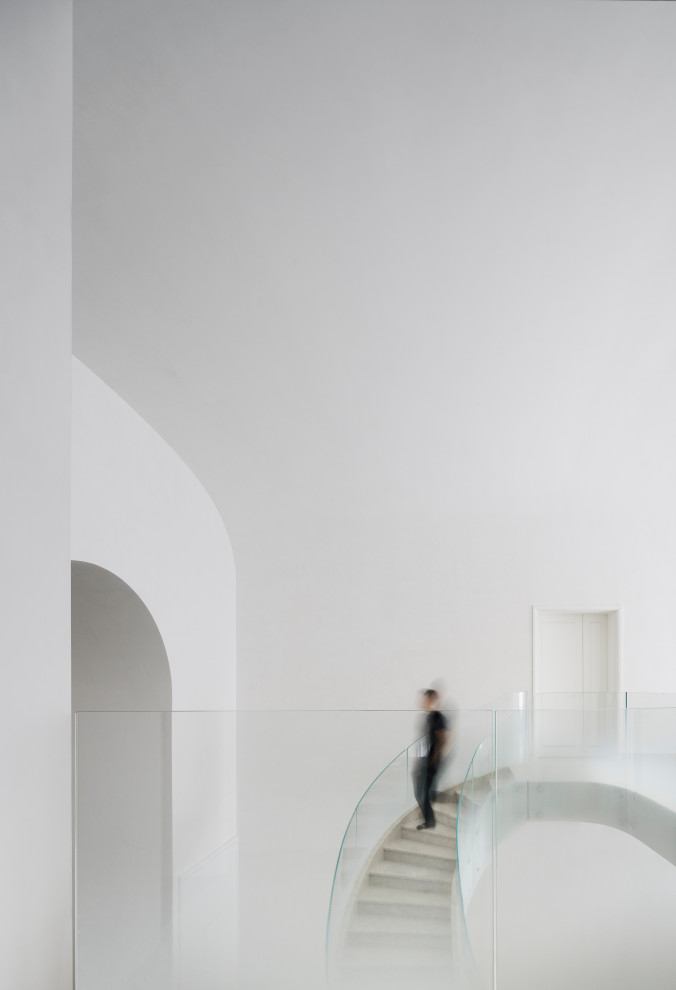 Ejemplo de escalera curva contemporánea extra grande con escalones de mármol, contrahuellas de mármol y barandilla de vidrio