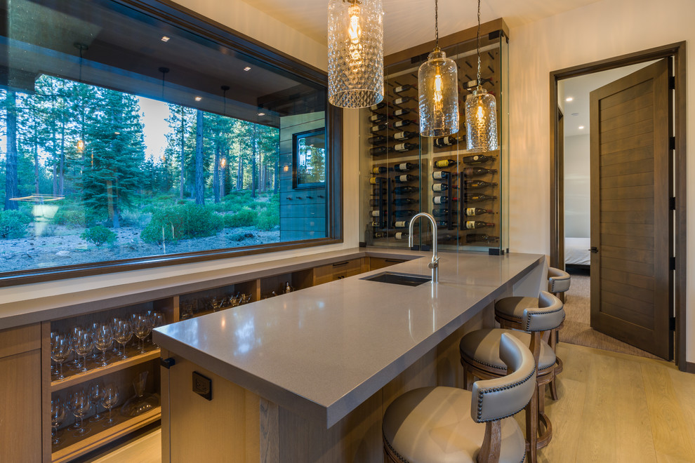 Photo of a mid-sized contemporary galley wet bar in Sacramento with an undermount sink, flat-panel cabinets, medium wood cabinets, quartz benchtops, light hardwood floors and brown floor.