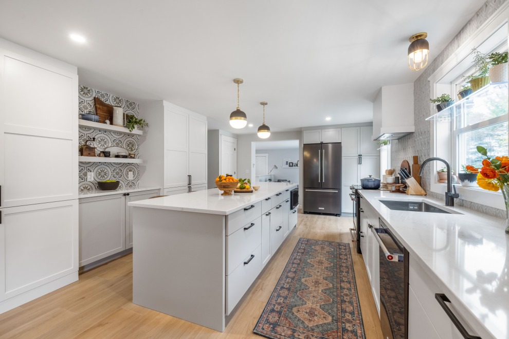 Eat-in kitchen - mid-sized transitional galley porcelain tile and brown floor eat-in kitchen idea in Portland Maine with an undermount sink, shaker cabinets, white cabinets, quartz countertops, blue backsplash, porcelain backsplash, stainless steel appliances, an island and white countertops