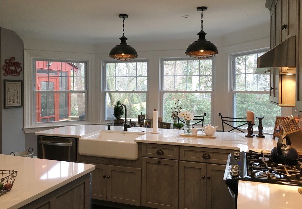 Large country l-shaped eat-in kitchen in Philadelphia with a farmhouse sink, shaker cabinets, grey cabinets, quartz benchtops, red splashback, brick splashback, stainless steel appliances, dark hardwood floors, with island, brown floor and white benchtop.