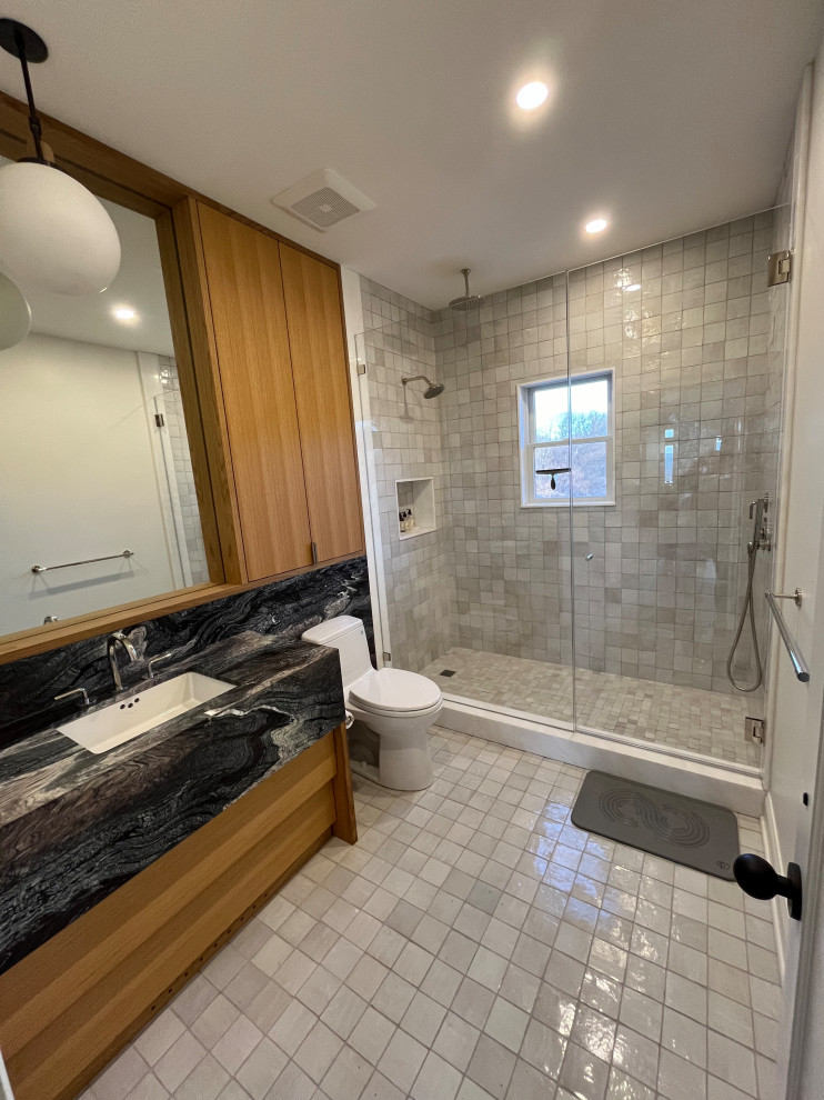 Cette image montre une grande salle de bain minimaliste en bois brun avec un placard à porte plane, une douche ouverte, WC à poser, un carrelage beige, des carreaux en terre cuite, un mur blanc, tomettes au sol, un lavabo encastré, un plan de toilette en granite, un sol beige, une cabine de douche à porte battante, un plan de toilette noir, une niche, meuble simple vasque et meuble-lavabo encastré.