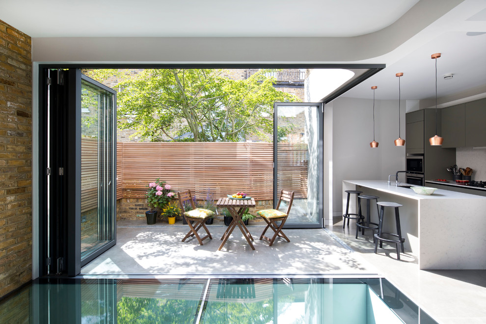 Contemporary kitchen/dining combo in London with white walls.