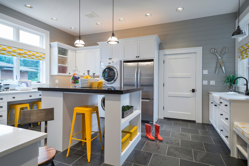 Country laundry room in San Francisco with a farmhouse sink, shaker cabinets, white cabinets, grey walls, a stacked washer and dryer and grey floor.