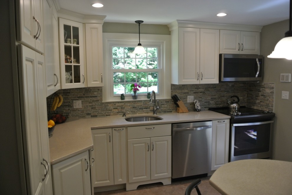 Inspiration for a transitional u-shaped porcelain tile and beige floor kitchen remodel in Boston with an undermount sink, raised-panel cabinets, white cabinets, beige backsplash, subway tile backsplash and stainless steel appliances