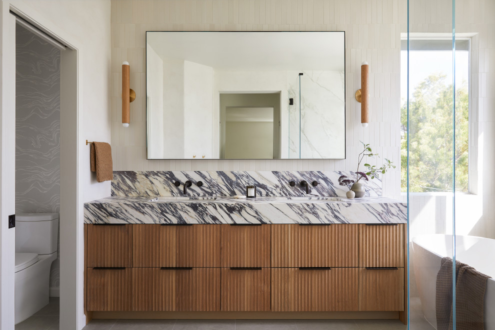 Inspiration for a large contemporary master beige tile and ceramic tile limestone floor, gray floor and double-sink bathroom remodel in San Francisco with light wood cabinets, a two-piece toilet, white walls, an undermount sink, marble countertops, a hinged shower door, purple countertops, a built-in vanity and flat-panel cabinets