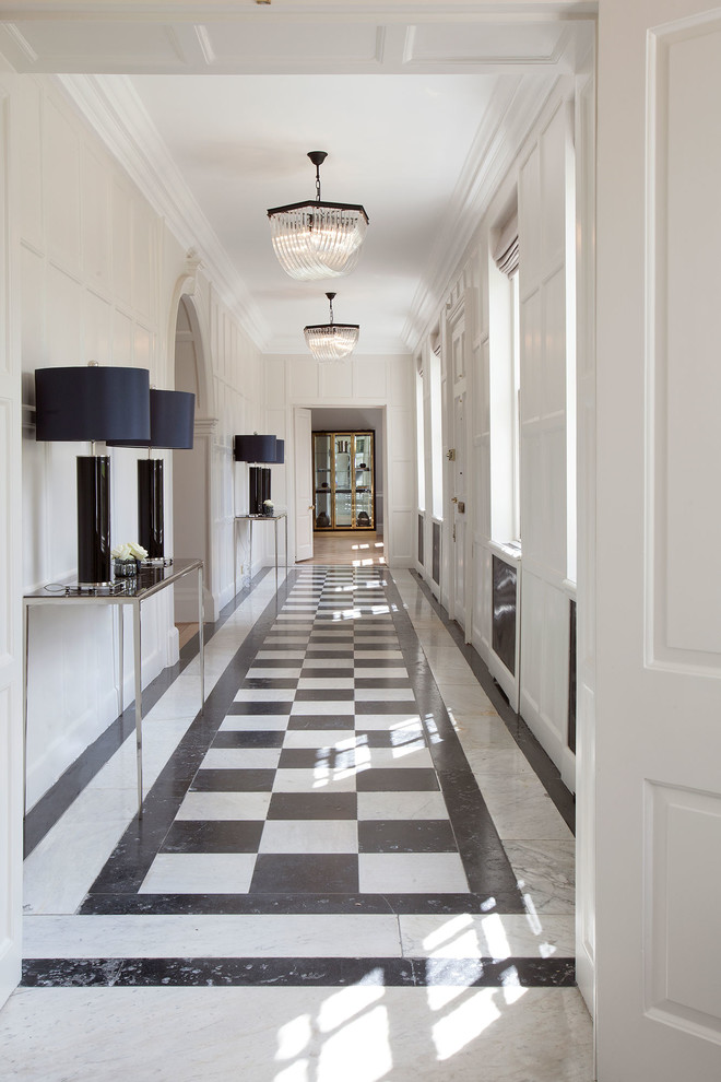 This is an example of an expansive transitional hallway in London with beige walls and marble floors.