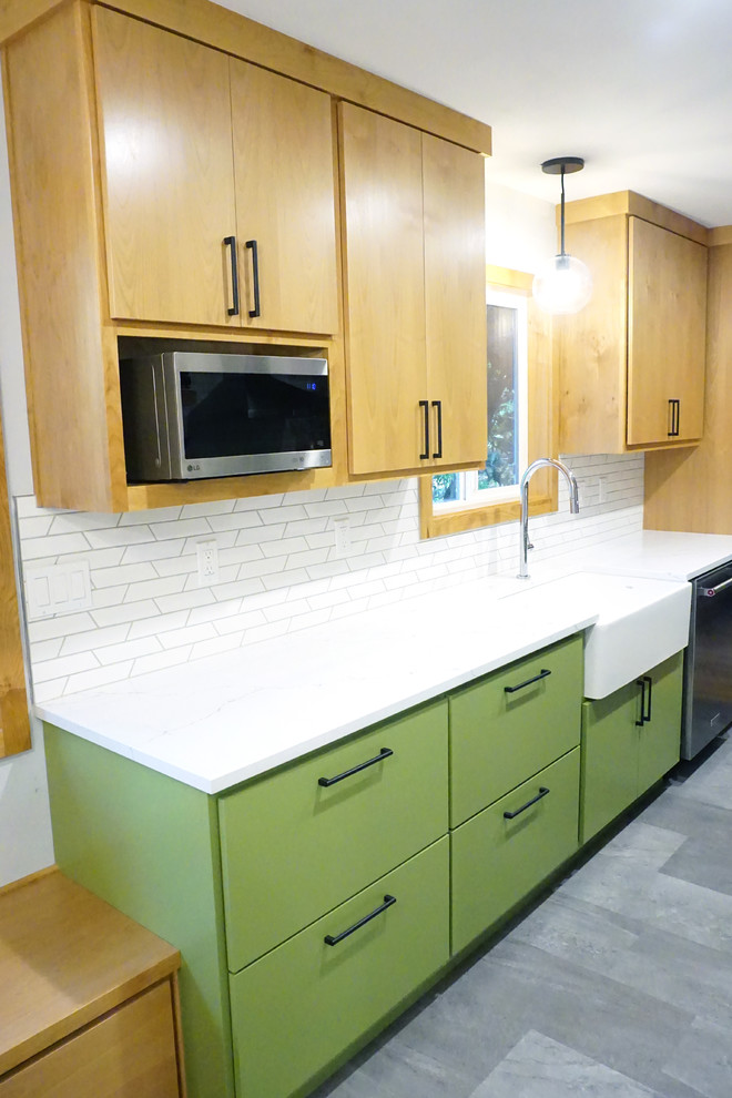 Design ideas for a mid-sized midcentury galley kitchen in Portland with a farmhouse sink, flat-panel cabinets, medium wood cabinets, quartz benchtops, white splashback, porcelain splashback, stainless steel appliances, vinyl floors, grey floor and white benchtop.