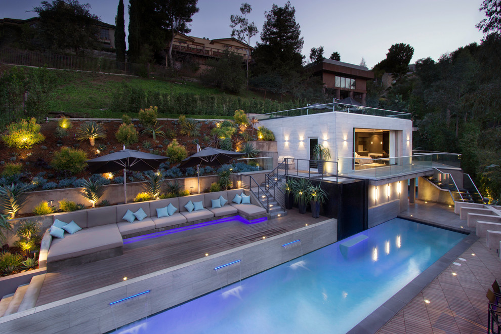 Photo of a large contemporary backyard rectangular lap pool in Los Angeles with a pool house and decking.