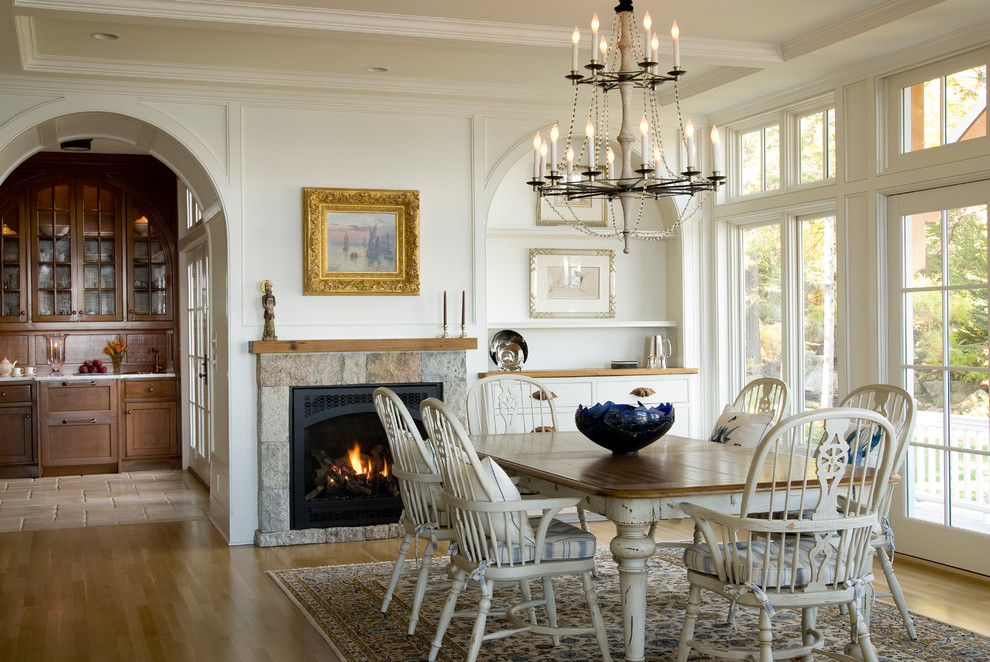 Inspiration for a traditional dining room in DC Metro with white walls, medium hardwood floors, a standard fireplace and a stone fireplace surround.