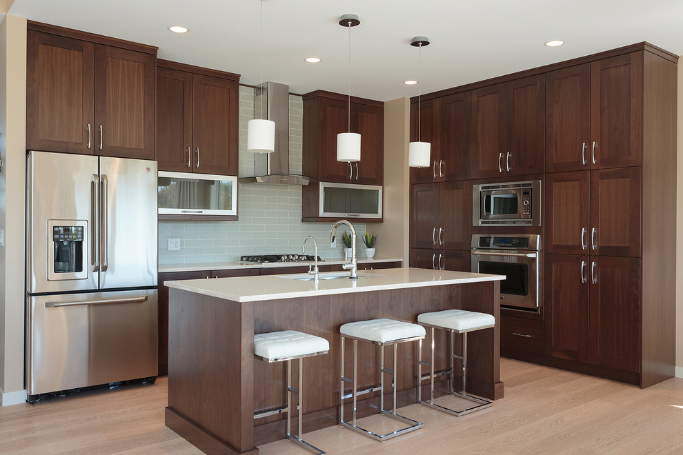 Inspiration for a transitional light wood floor kitchen remodel with an undermount sink, dark wood cabinets, stainless steel appliances and an island