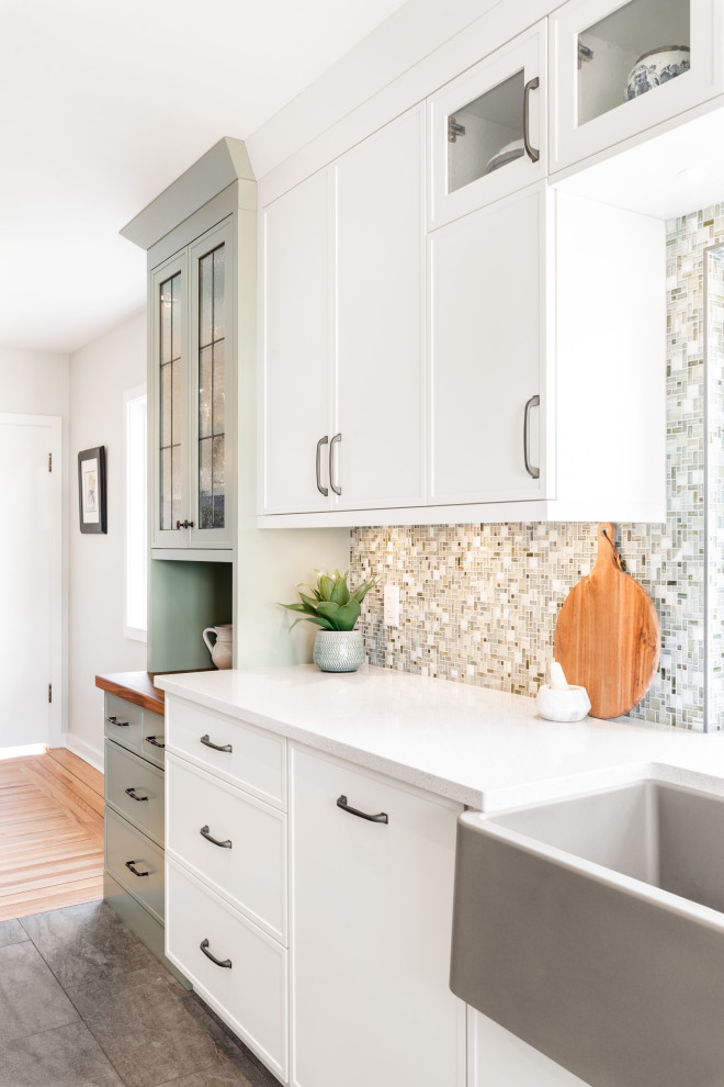 Small country single-wall eat-in kitchen in Vancouver with a farmhouse sink, shaker cabinets, white cabinets, quartz benchtops, multi-coloured splashback, mosaic tile splashback, stainless steel appliances, vinyl floors, with island, grey floor and white benchtop.